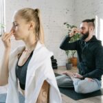 A man and woman practicing mindful yoga and breathing exercises in a serene indoor setting.