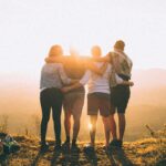 A group of friends embrace while enjoying a breathtaking sunrise over the Brazilian highlands.